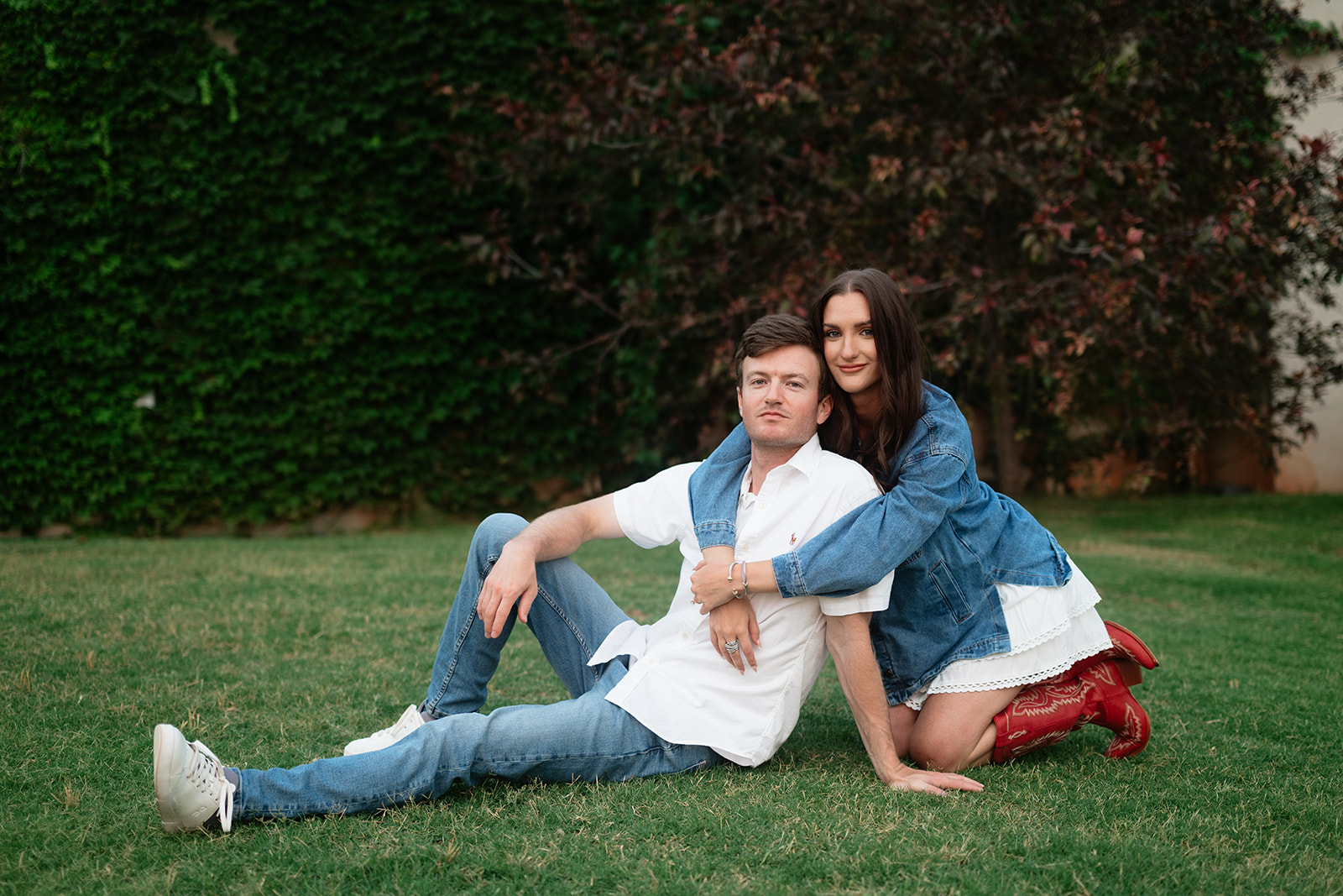 Couple sitting together on the lawn during their engagement session at The Baumberhof wedding venue in Edmond, Oklahoma.